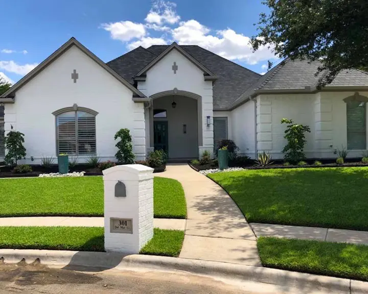 Beige brick elevation lightened, trim and door recoated — after