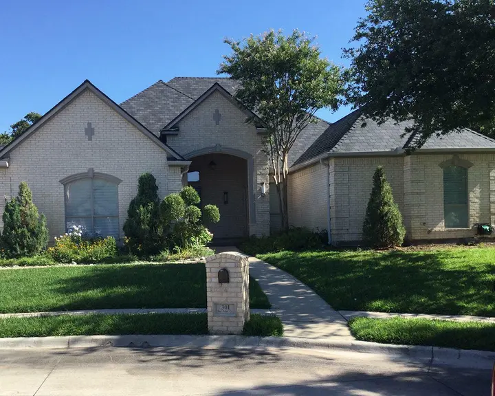 Beige brick elevation lightened, trim and door recoated — before