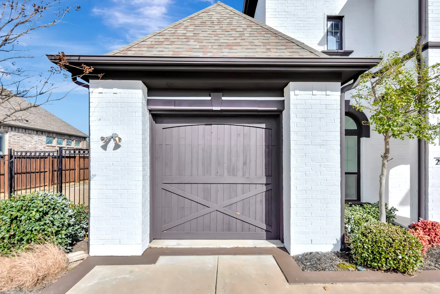 Single carriage garage door in gray, flanked by white painted brick piers under a hipped roof