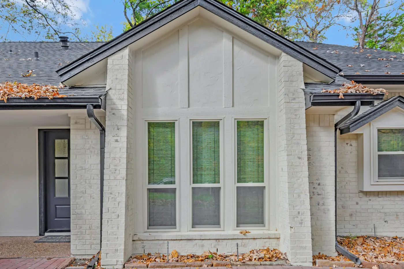 Painted brick and board gable above a triple window, beside the front door