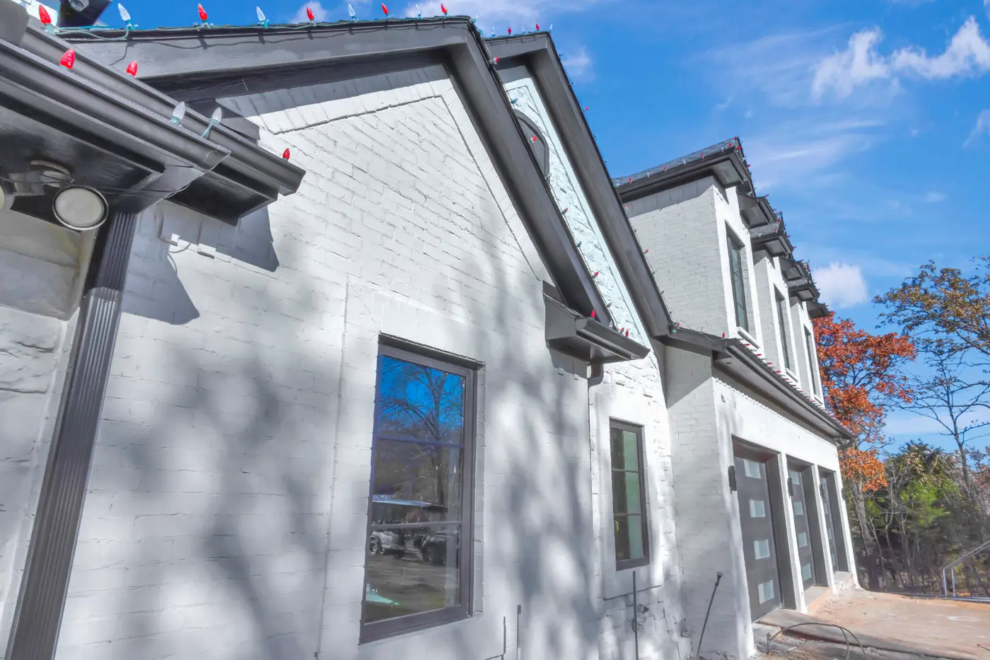 Painted brick gable end with a tall window, looking along the elevation to the garages