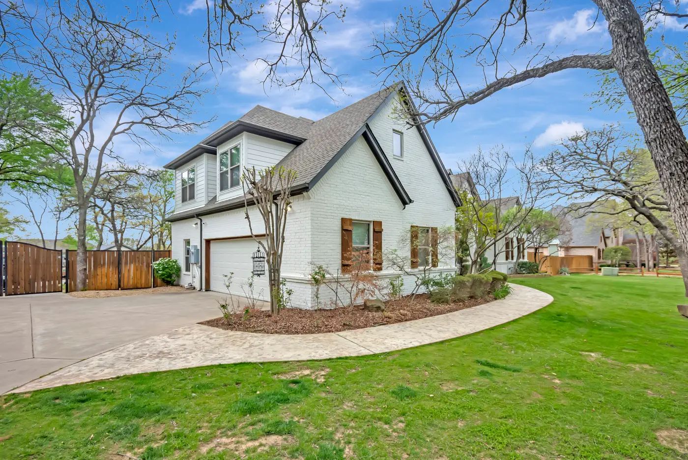 Painted brick home from the drive, with a single garage door and a curving curb