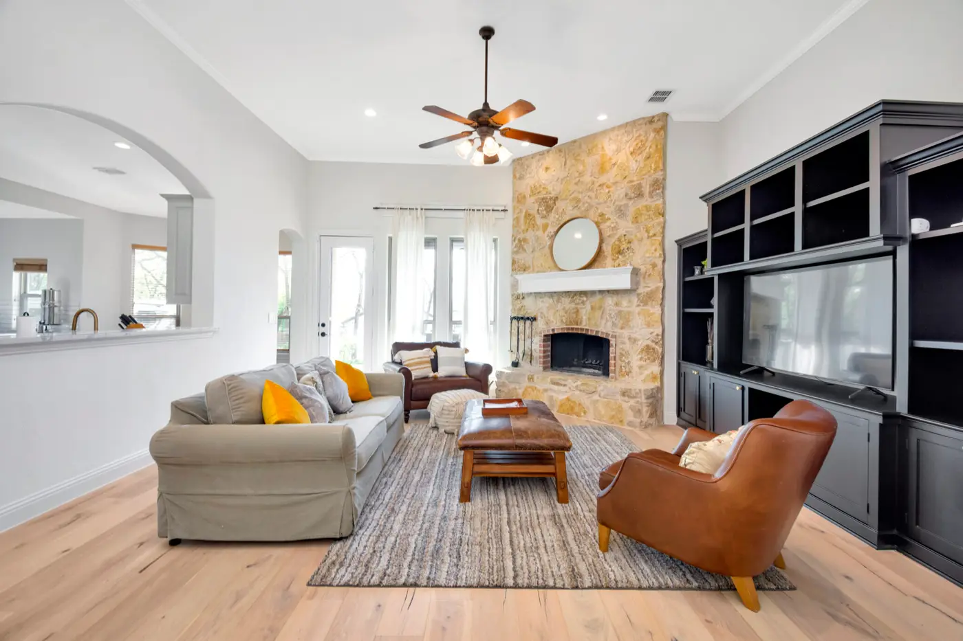 Open living room with painted walls and ceiling, a stone fireplace and dark media units
