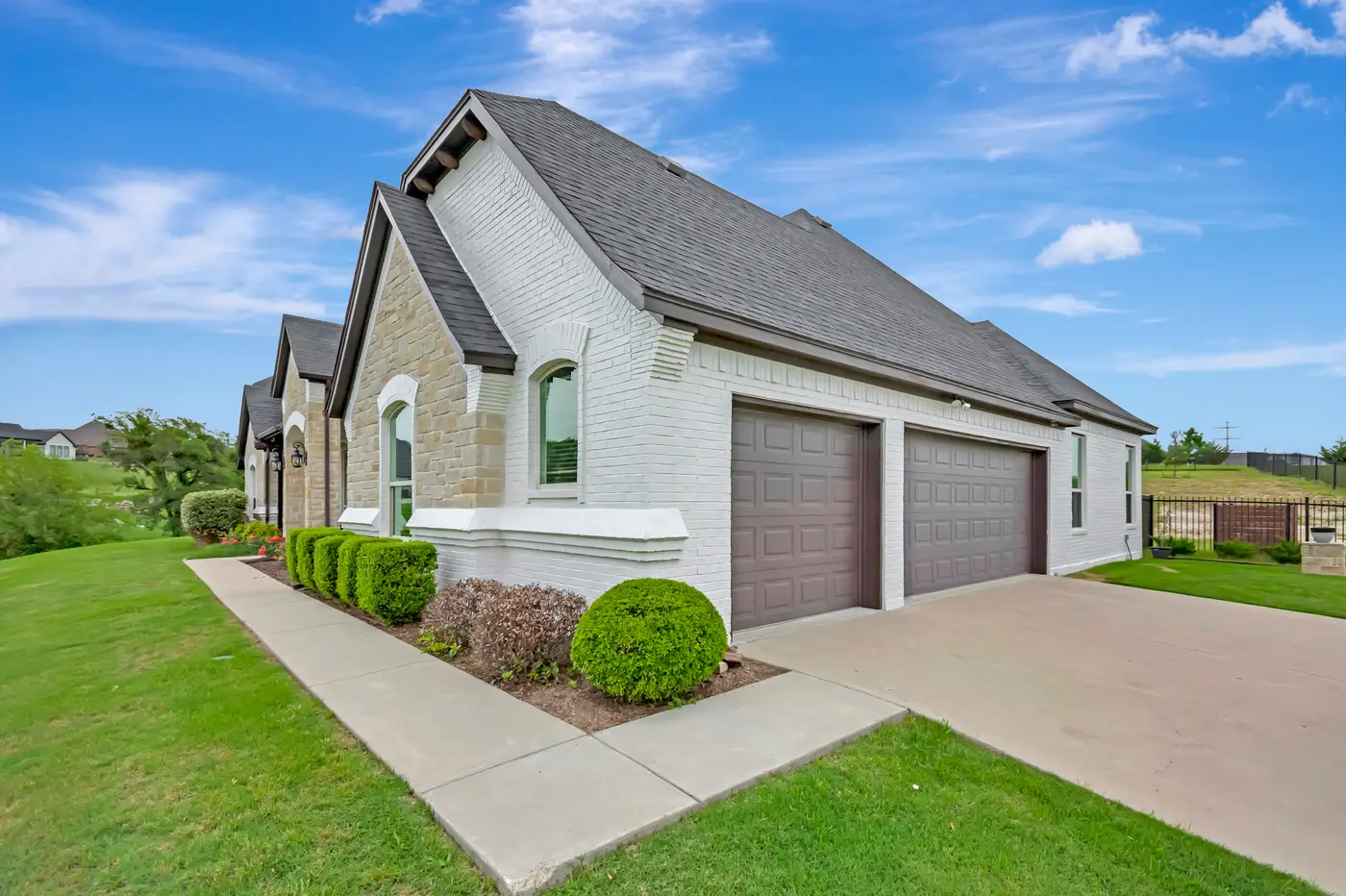 Wide front elevation of a painted brick and stone single-story seen across a large lawn
