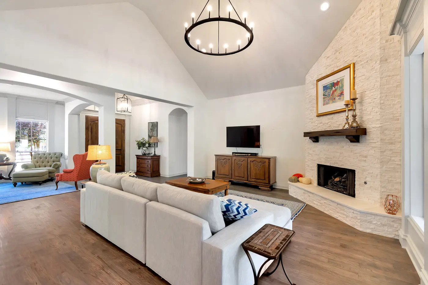 Vaulted living room painted in warm white, with a stacked-stone chimney breast