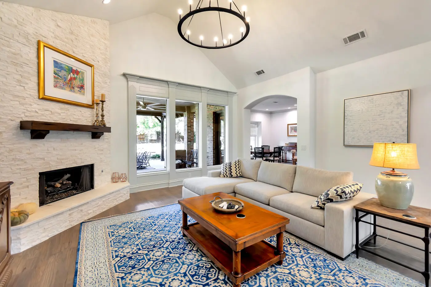 Living room with a painted vaulted ceiling, stone fireplace and archway to the dining area