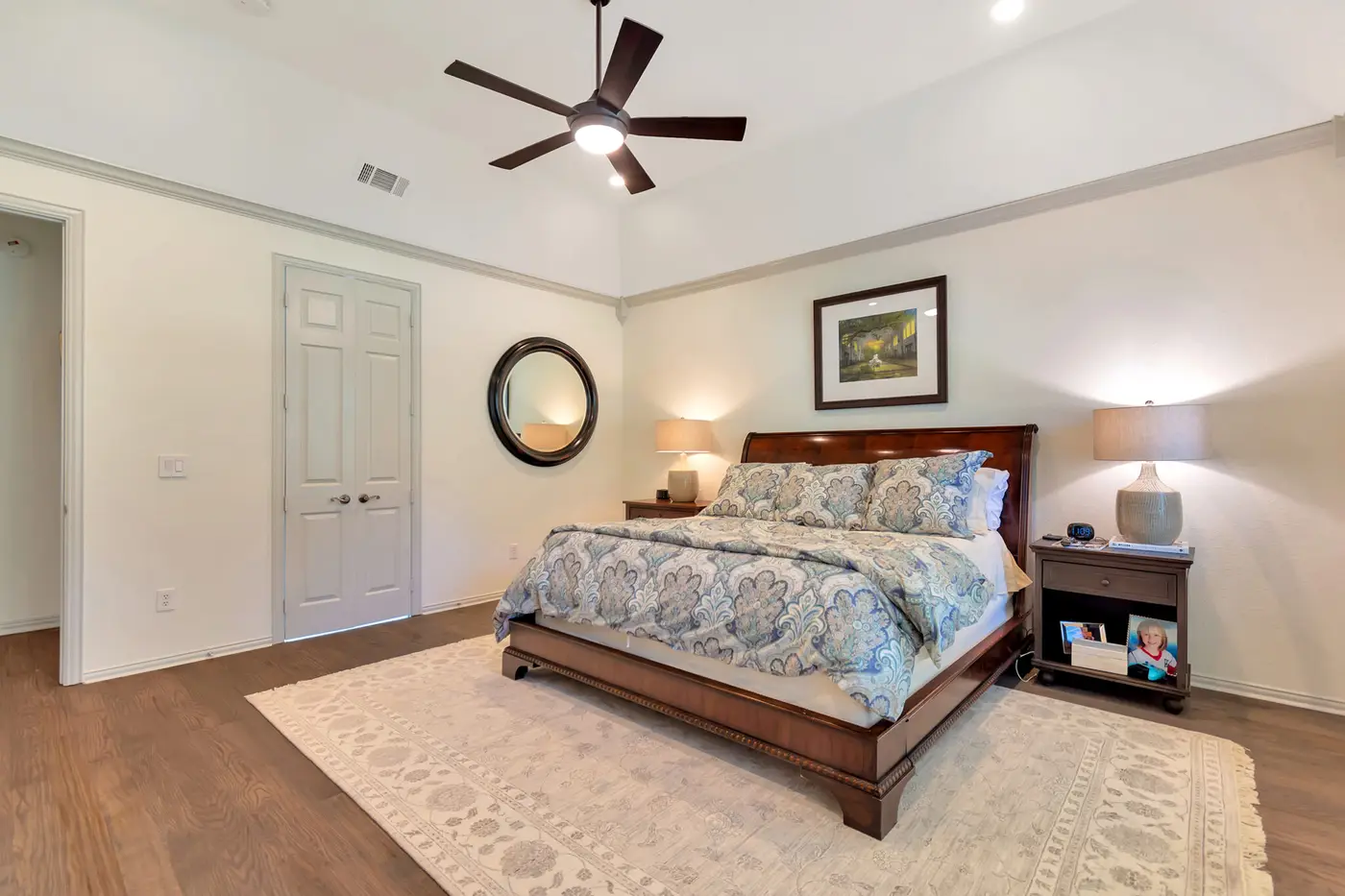 Repainted main bedroom with a sleigh bed, ceiling fan and paneled door