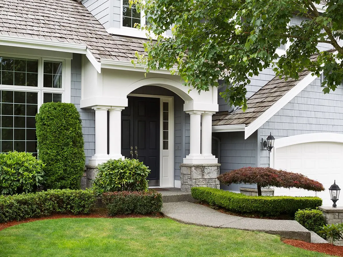 Newly painted exterior of a North American home during summertime with green grass and flower beds.