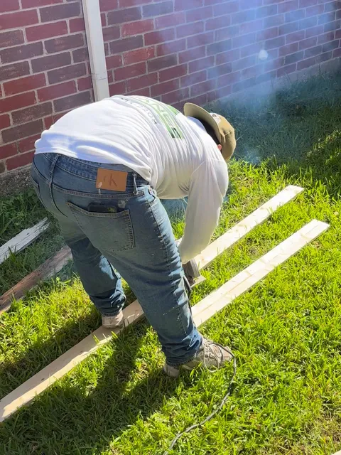 A crew member power-washing a brick wall, the spray plume visible against the masonry