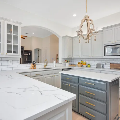 Kitchen with painted white cabinetry, marble island and subway tile