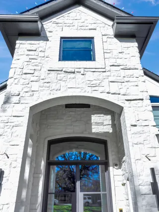 Arched entry of a brick home finished in white mineral masonry paint